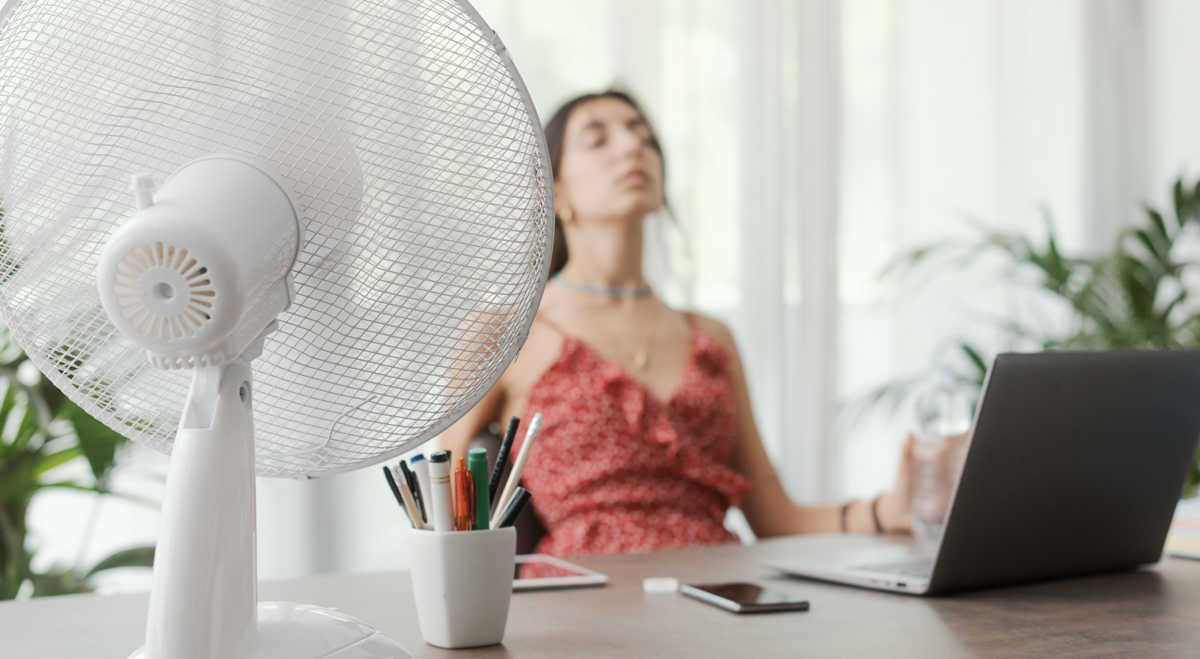 Woman with fan trying to work in a heatwave