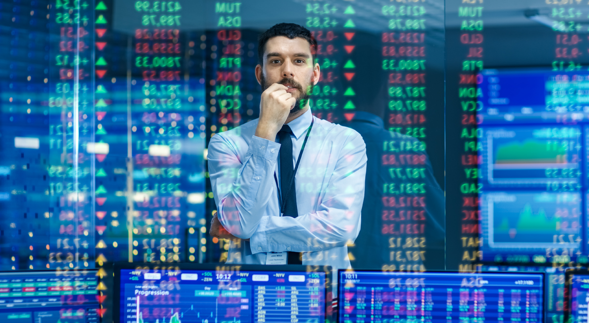 Man standing in front of stock charts on screens